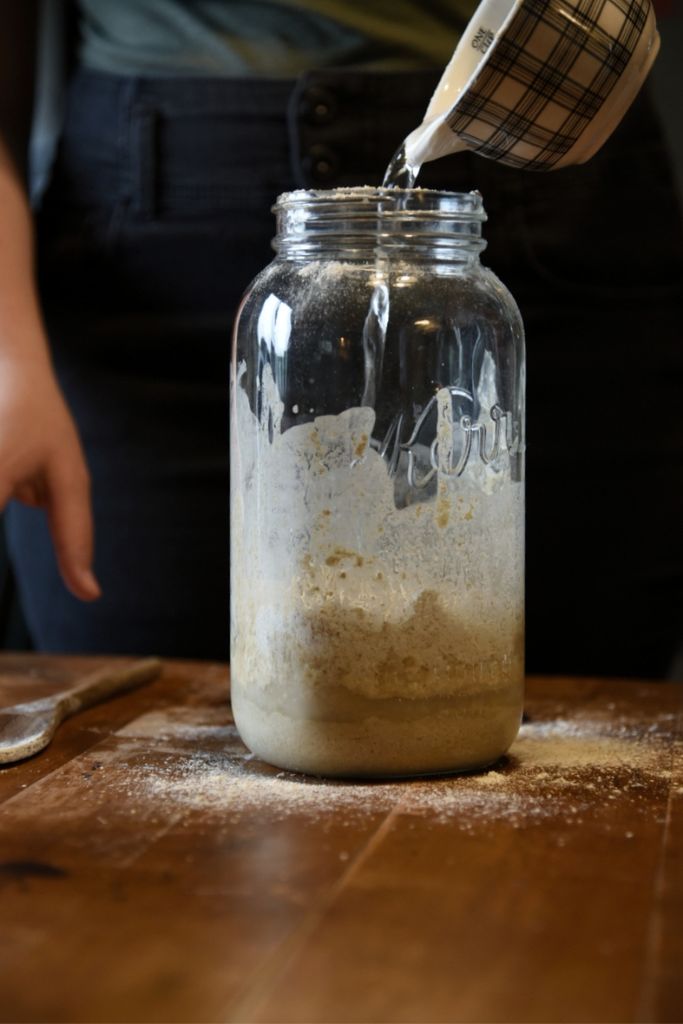 adding water to a jar of sourdough starter