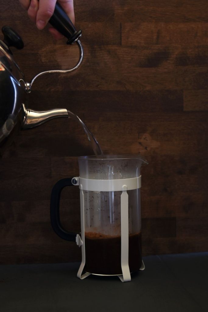pouring water from a tea pot into a french press