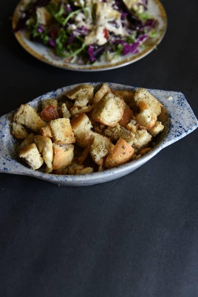 a dish of croutons with a salad in the back round