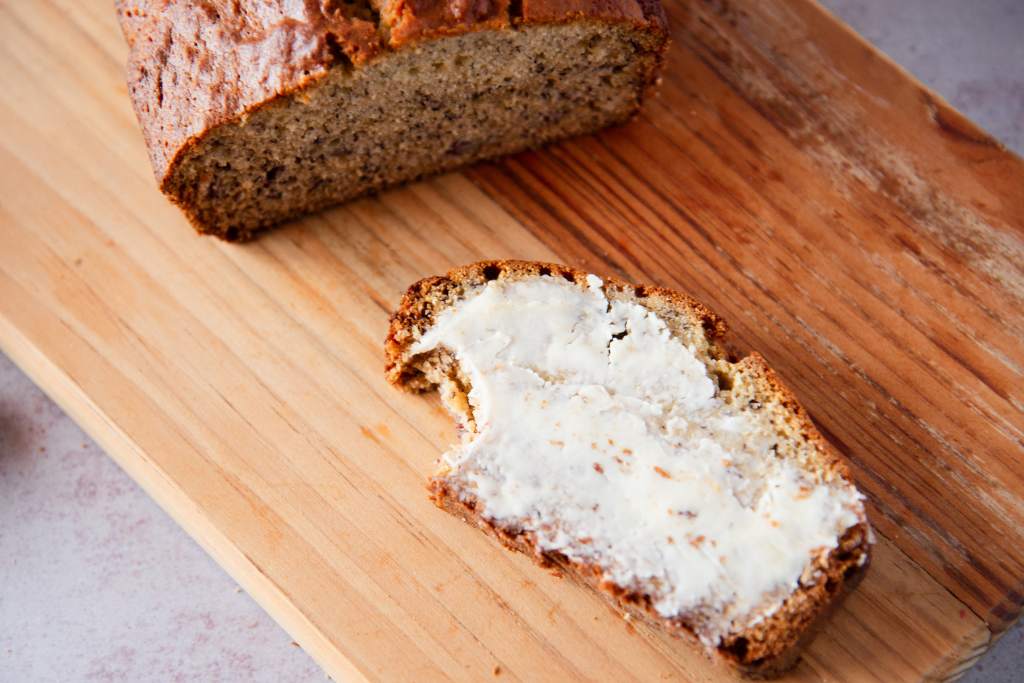 a slice of banana bread with a bite taken out of it, next to a loaf of banana bread