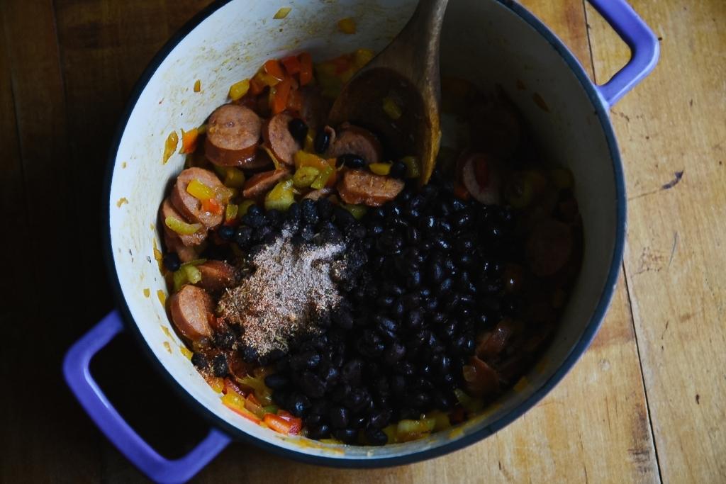 overhead image on cooked meat and veggie mixture with black beans and seasoning on top