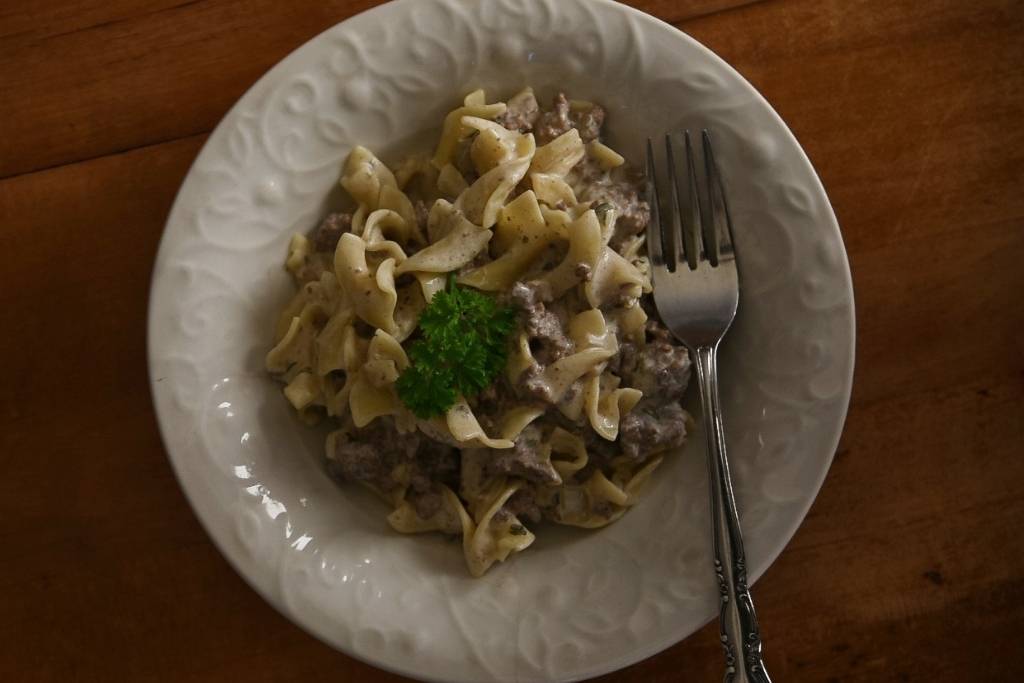 a bowl of stroganoff with a fork in it and some parsley on top.