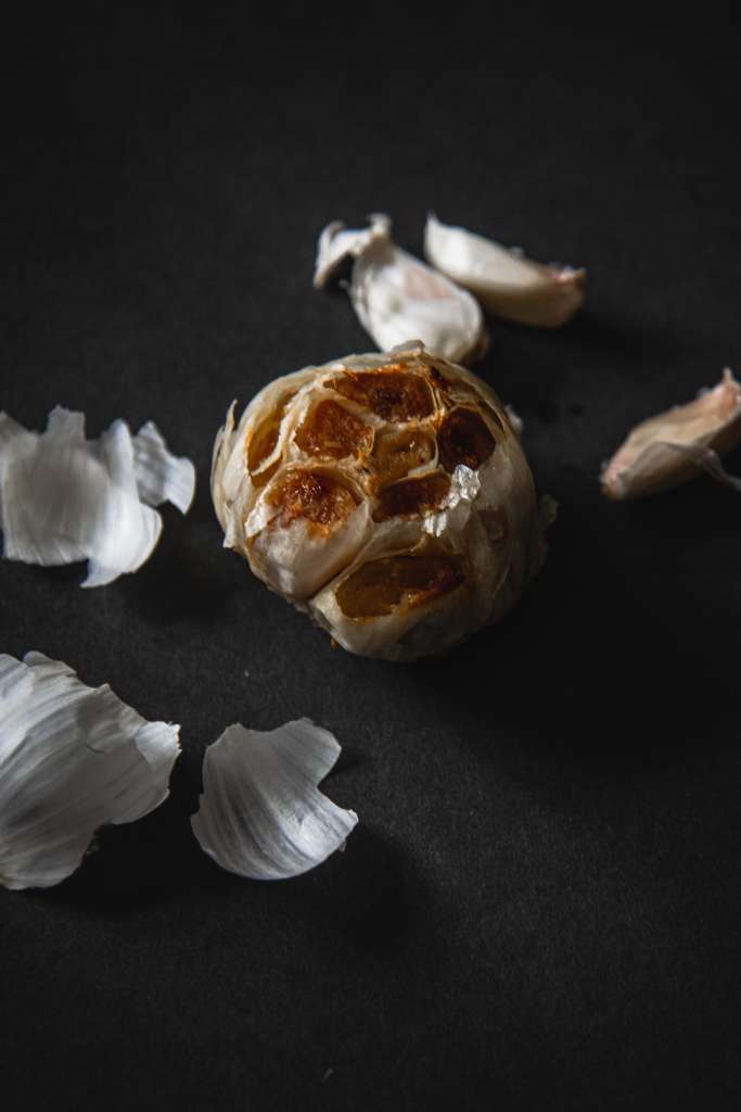 a head of garlic with some cloves behind it and some peel next to it