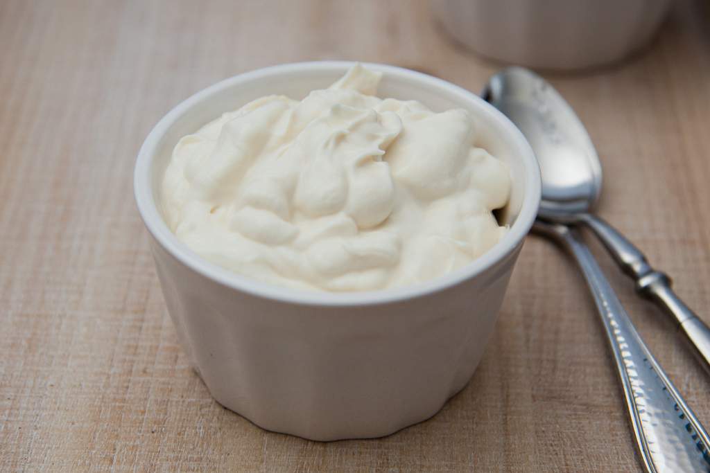 a white dish of vanilla yogurt, with some spoons next to it