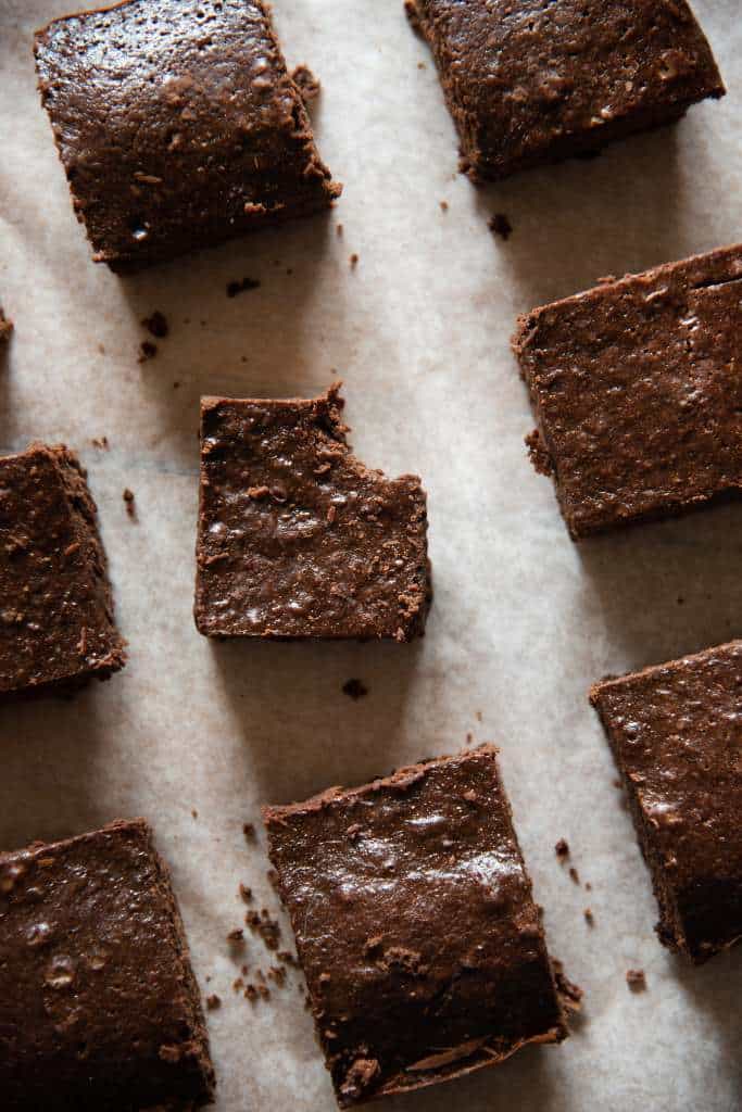 brownies spaced out on a piece of parchment paper, the brownie the center has a bite taken out of it