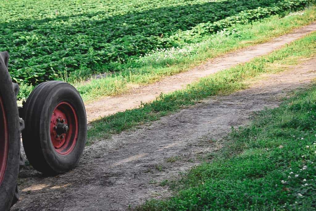 the wheels of a tracker turning down a path in a farm field