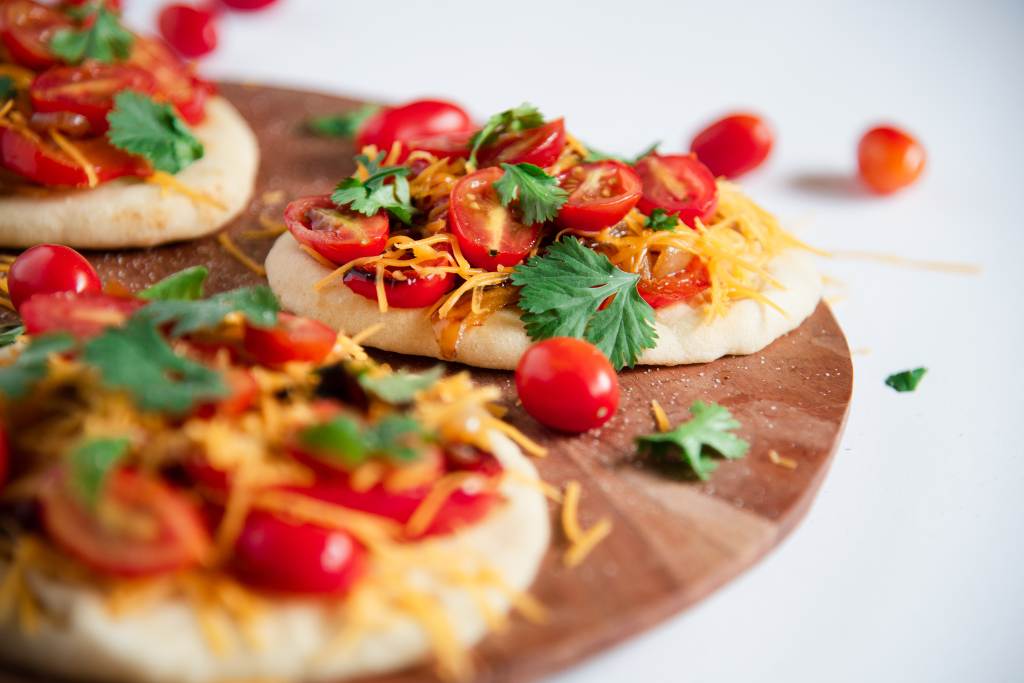 a close up of a sandwich on a wooden plate, there are some tomatoes and other sandwiches around it 