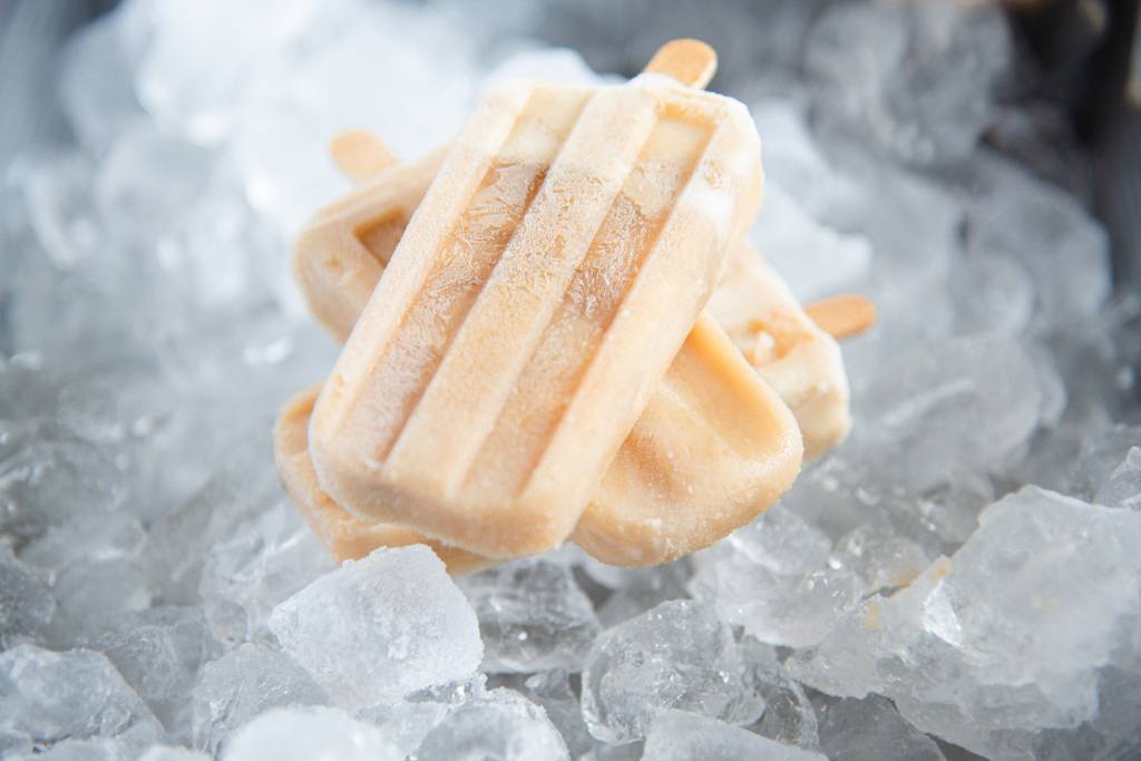 three root beer ice cream bars stacked on top on each other, on a dish full of ice.