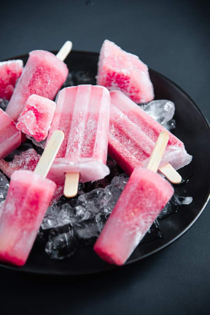 a close of popsicles, frozen watermelon chunks and ice on a black plate 