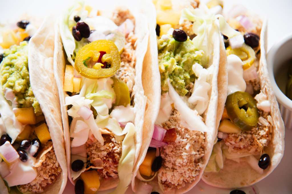a close up of four fish tacos from the side