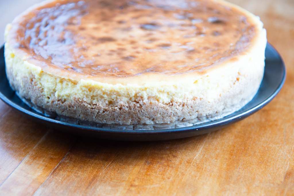 an slightly angled photo on an uncut cheesecake on a black plate