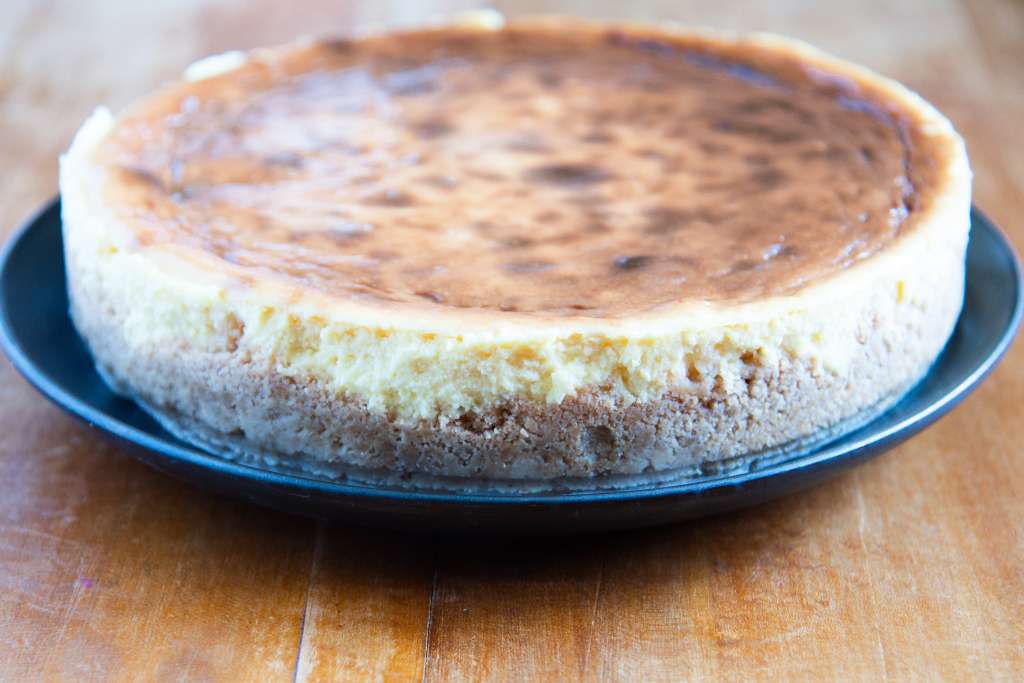 an uncut cheesecake on a black plate 