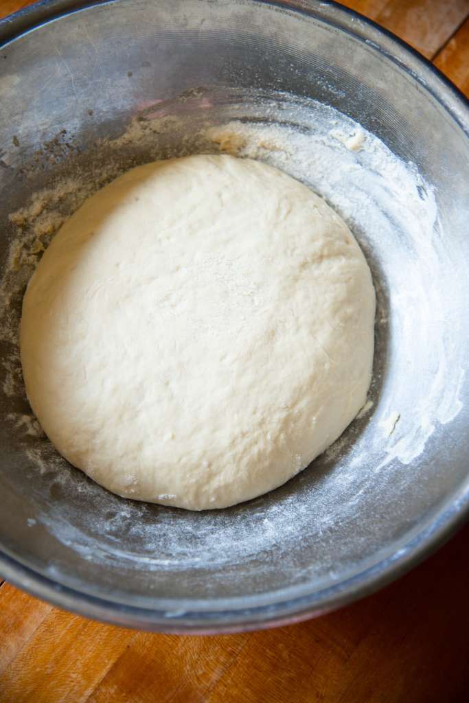 risen dough in a sliver metal bowl