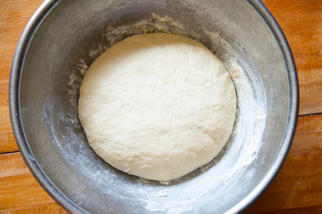 an overhead shot of risen dough in a sliver metal bowl