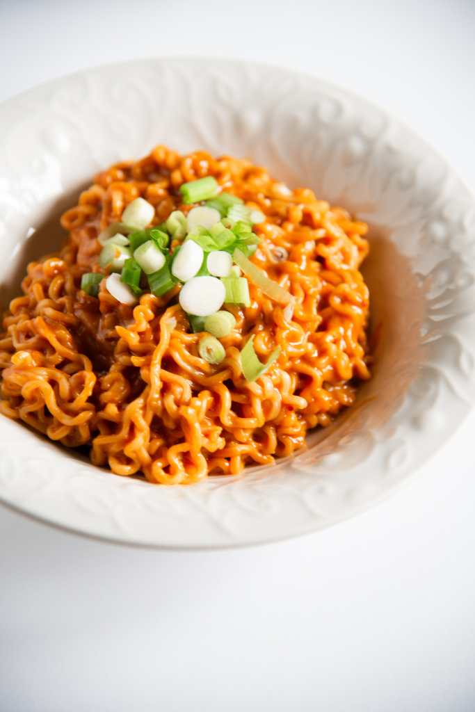 a bowl of spicy peanut ramen with sliced green onions on top