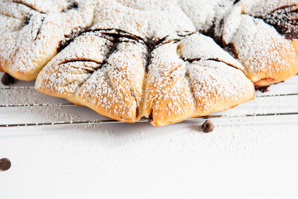 a close up of a finished star bread with powdered sugar on it 