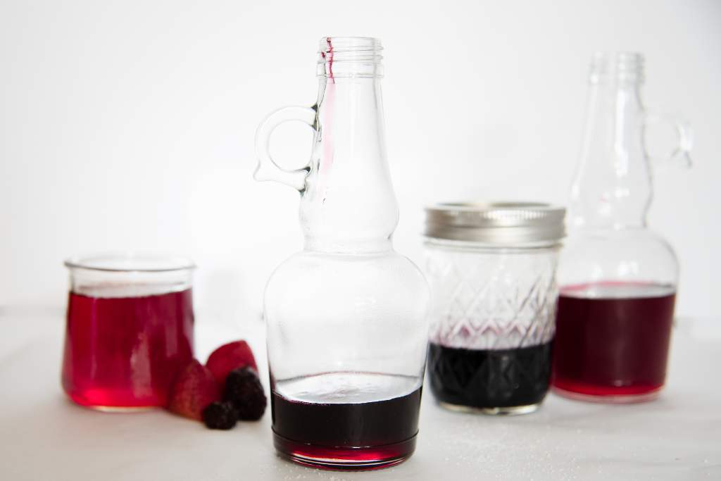 different jars and bottle of berry simple syrup