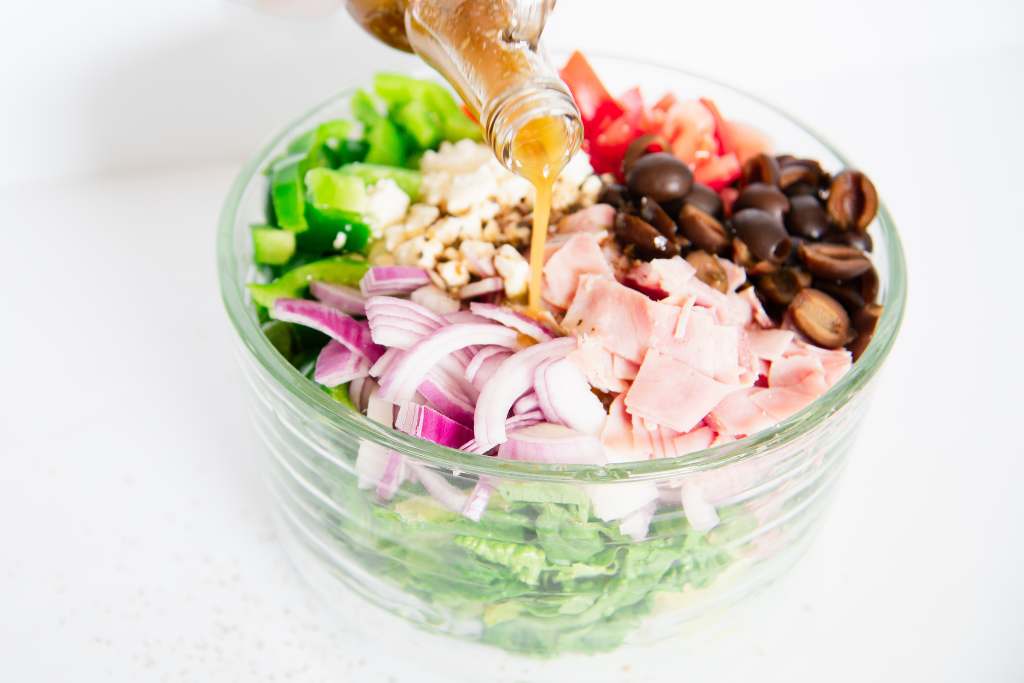 salad dressing being poured over a salad