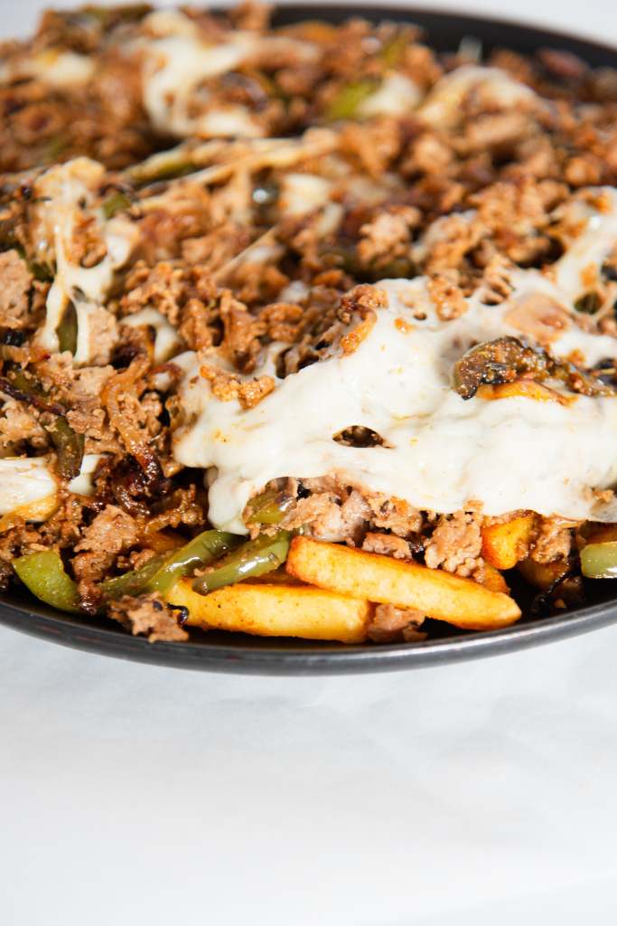 a close up of Philly cheeseteak fries