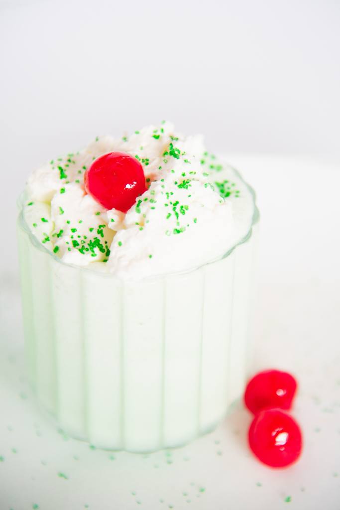 a finished shamrock shake with a cherry on top and two cherries next to it