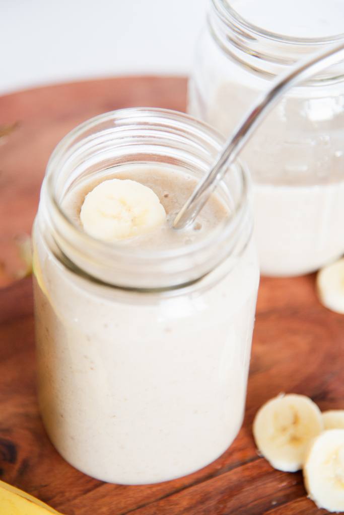 a close up of a banana shake with a straw in it, and a banana slice on top