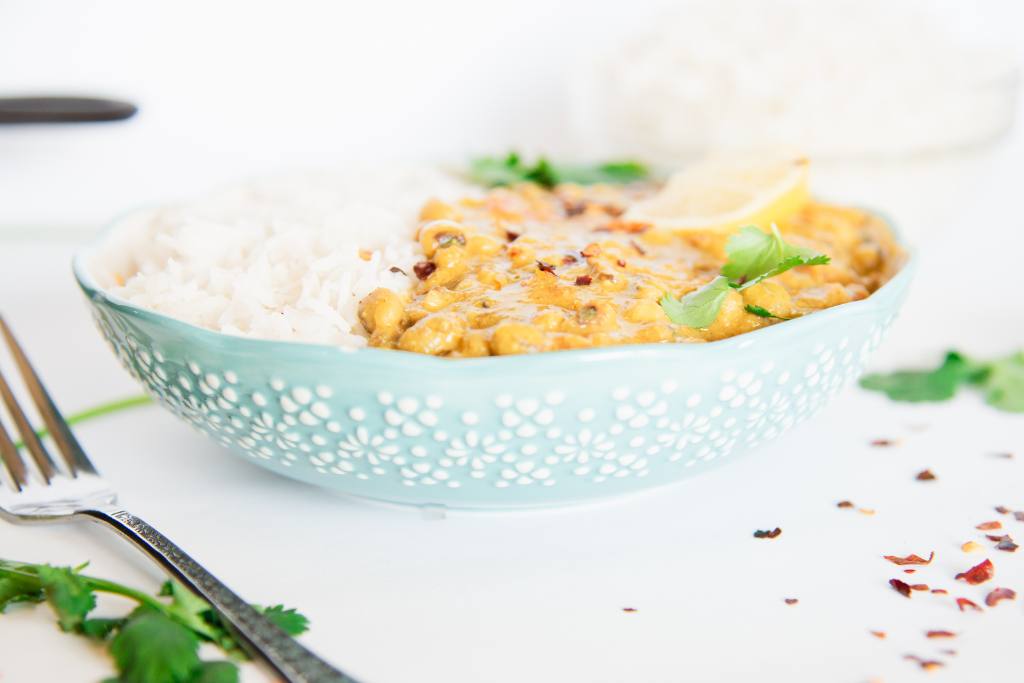 a blue bowl of curry and rice with a fork next to it