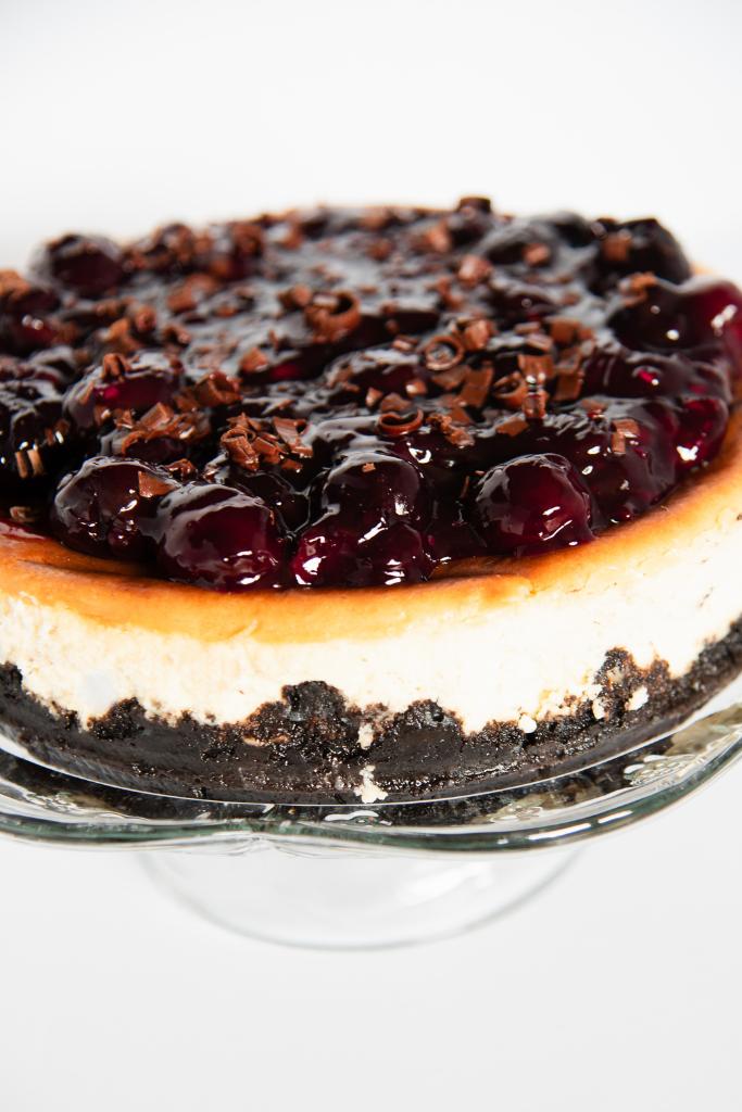 a black forest cheesecake on a glass cake stand