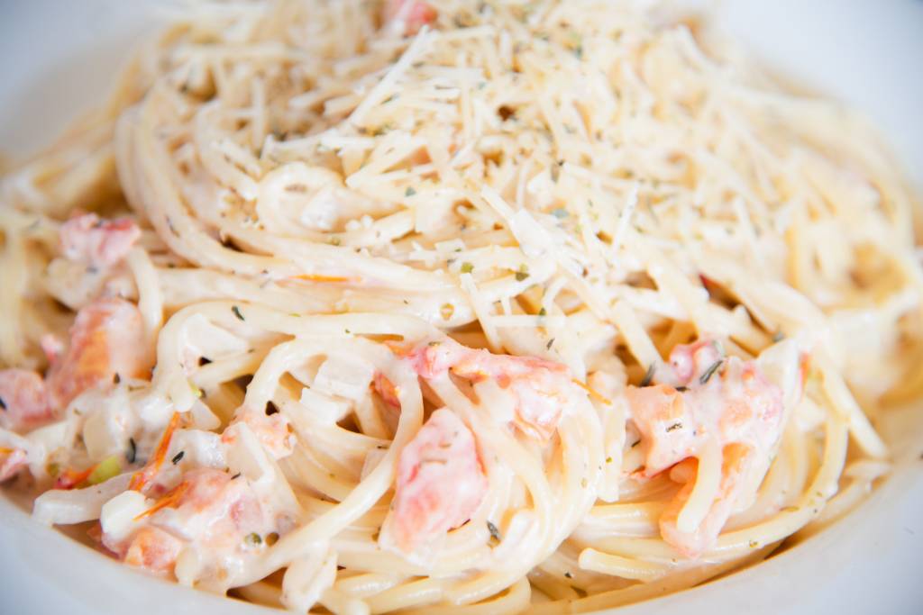 a close up of pasta with creamy white wine pasta sauce with shredded cheese on top