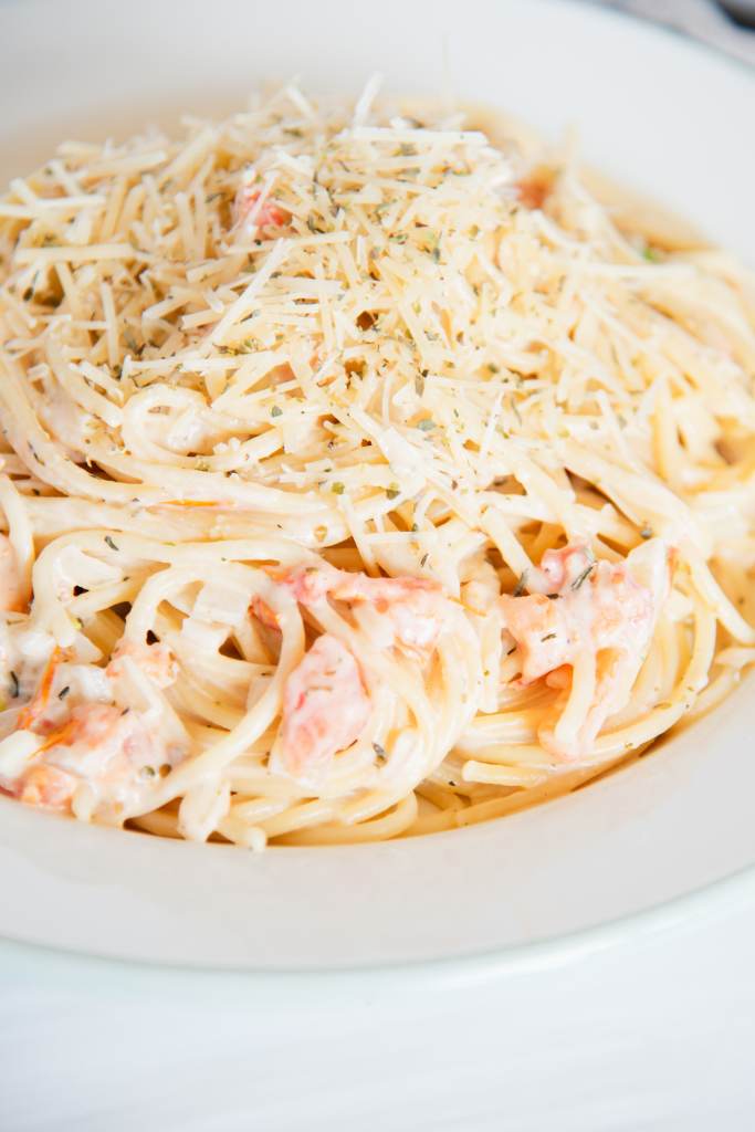 a place of pasta with white wine sauce and shredded cheese