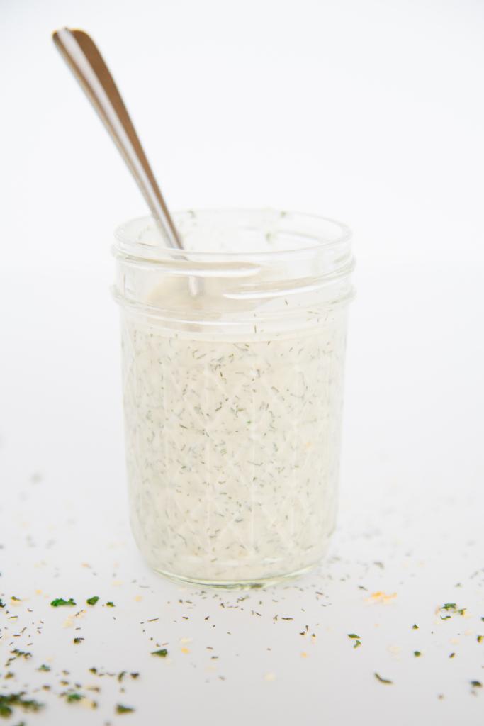 a jar of ranch dressing from the side with a spoon in it 