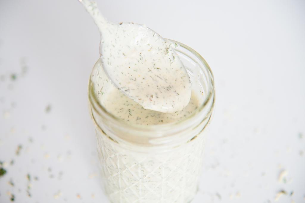 a spoon of ranch dressing pulling out of a jar of dressing