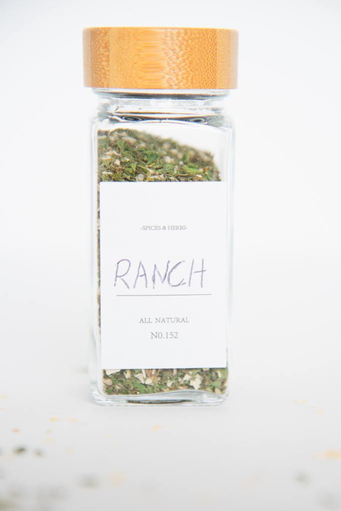 a close up of a glass spice jar of ranch seasoning mix, it has a label that says ranch 