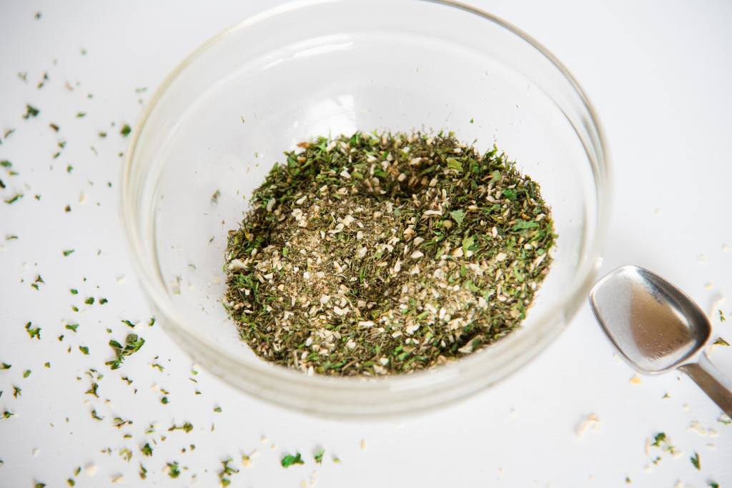 a glass bowl with spices in it, and a measuring spoon next to it