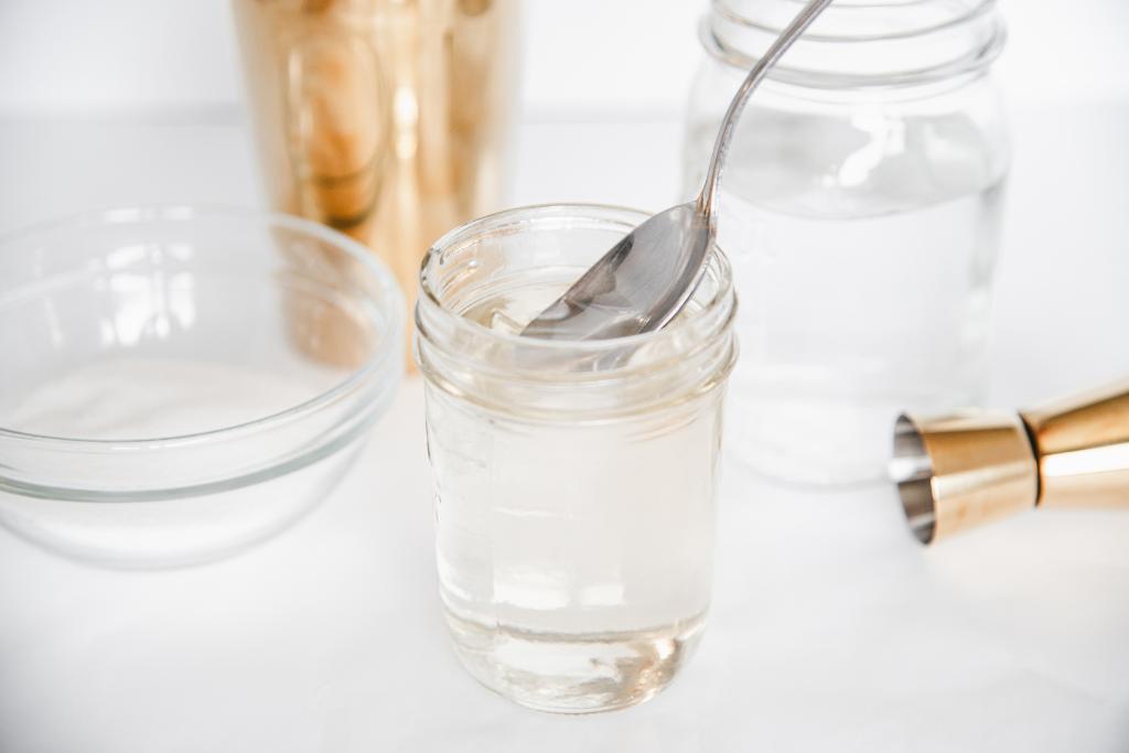 a spoon being dipped into a jar of simple syrup