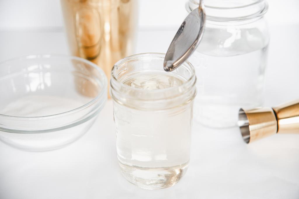 a spoon being lifted out of a jar of simple syrup