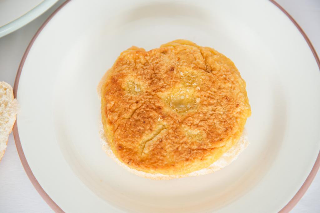 a close up of a chickpea veggie burger on a plate, you can see part of a hamburger bun next to the plate