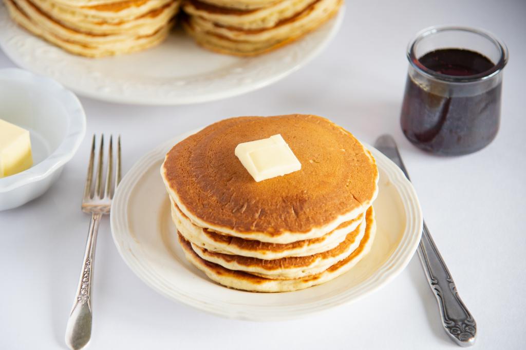 a stack of pancakes on a plate with butter on top of them.