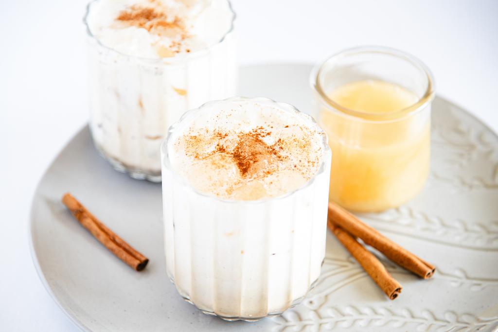 two iced breves with cinnamon sprinkled on top, there some cinnamon sticks next to them and a jar of honey as well