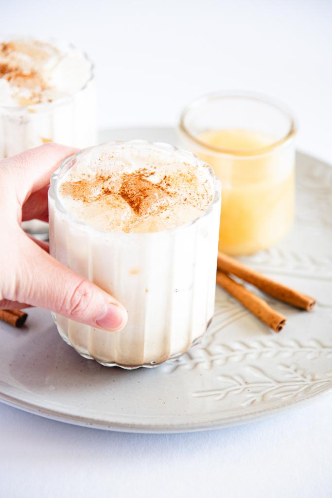 someone picking up a breve off a plate, there is a jar of honey and two cinnamon sticks next to it