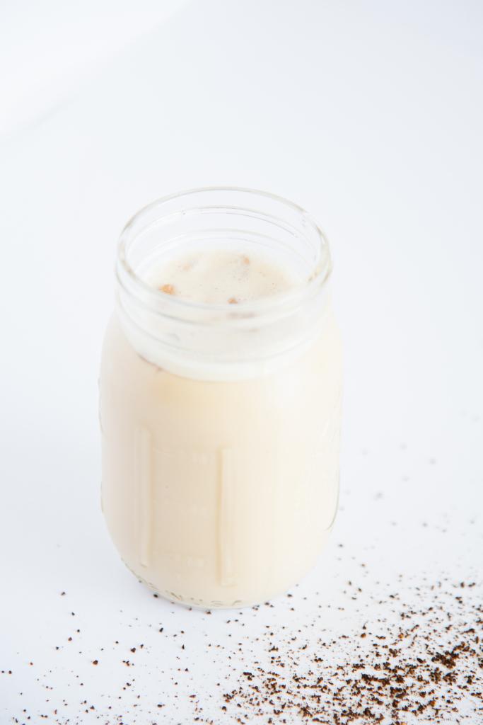 a jar of iced coffee with coffee ground spilled around it