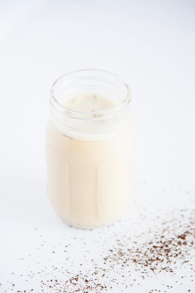 a jar of iced coffee with with coffee ground spilled around it