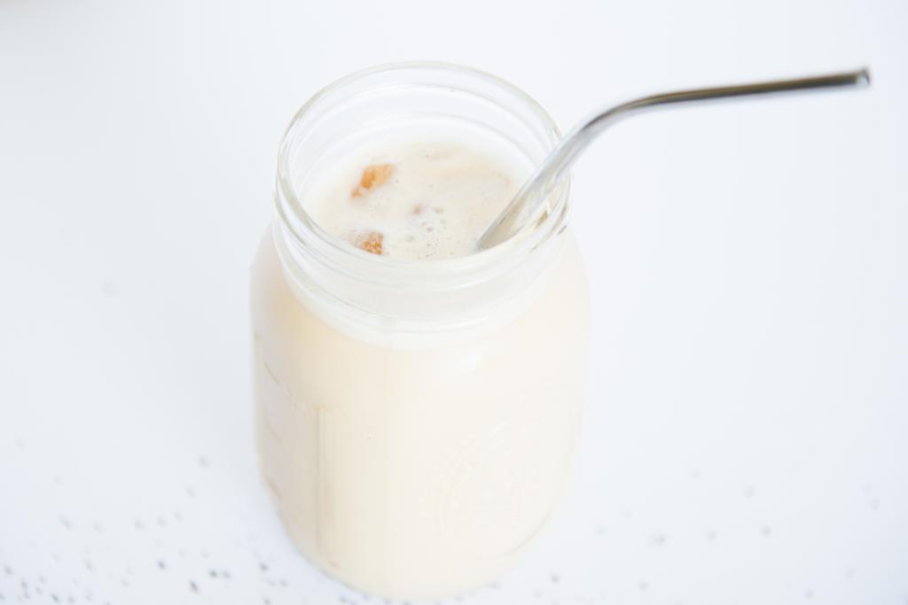 an overhead shot of a jar of iced coffee with a metal straw in it