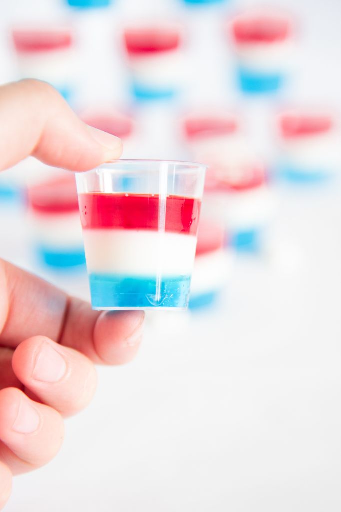 someone holding a jello shot in front of a stack of jello shots