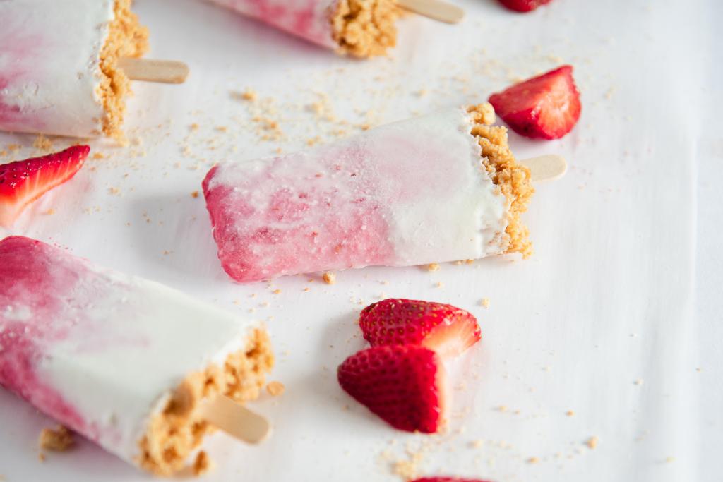 a close up of a Popsicle, with chopped strawberries around  