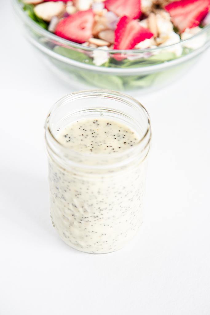 an over head picture of a jar of salad dressing, you can see part of a bowl of salad behind it 