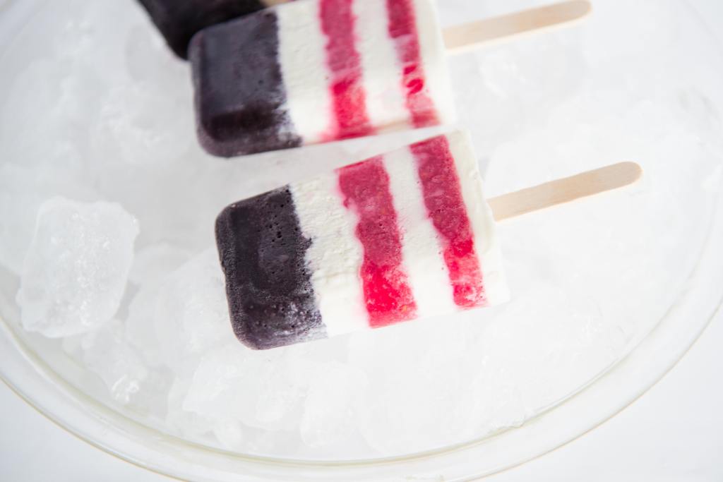 a close up of a red white and blue popsicle on a dish of ice