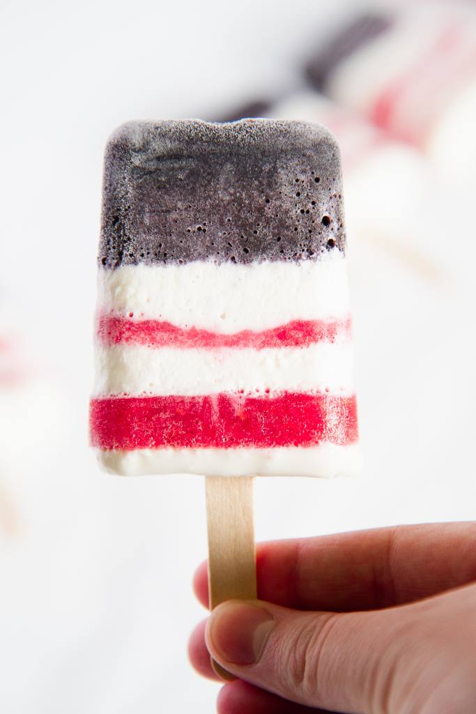 a close up of red, white, and blue Popsicle someone is holding 