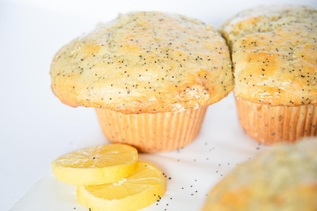 two muffins touching each other with a couple lemon slices in front of them