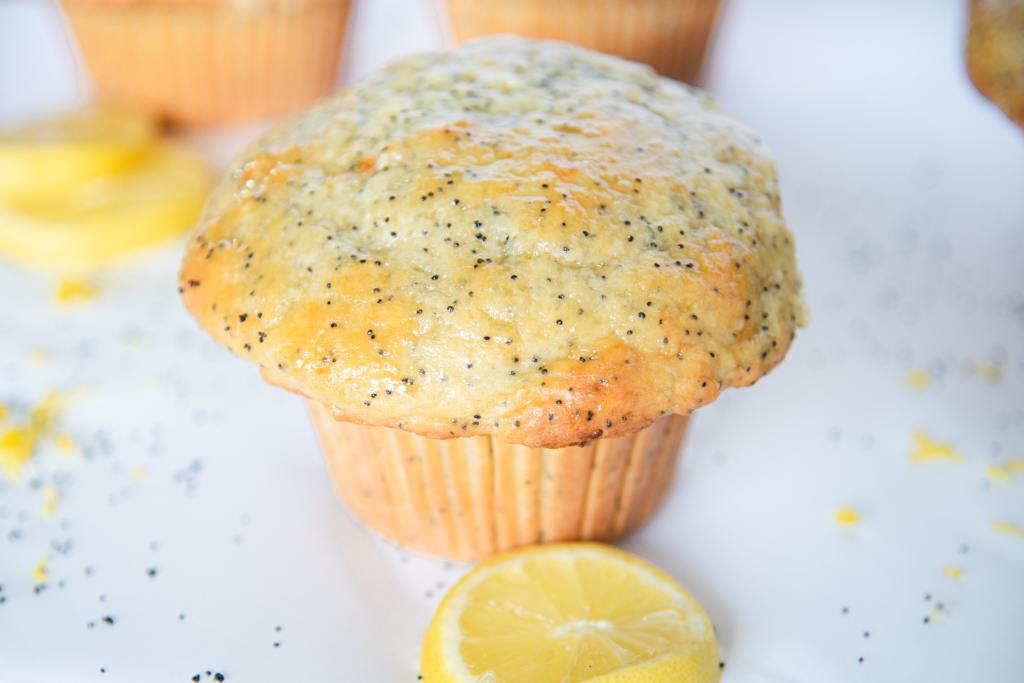 a close up of a lemon poppy seed muffin with a muffin slice in front of it