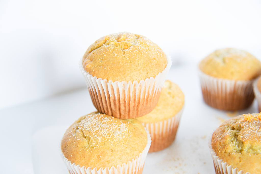 a muffin set on top of two other muffins, there is sugar sprinkled on top of all of them